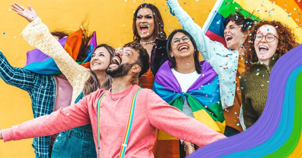 A group of people throwing confetti and laughing with a rainbow pride flag in the background.